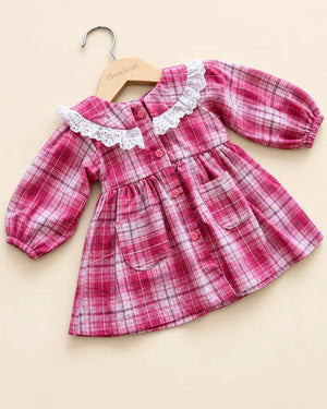 Pink plaid girls' frock with white lace collar, long sleeves, buttons, and front pockets
