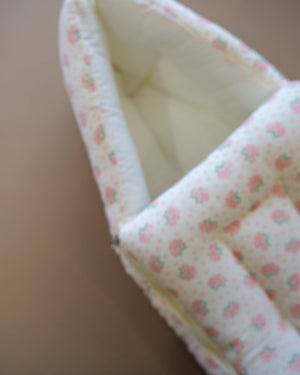 Off-white newborn swaddle sleeping bag with pink and green floral print
