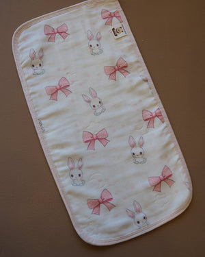 Printed off-white baby burp cloth with playful animal motifs and rounded edges
