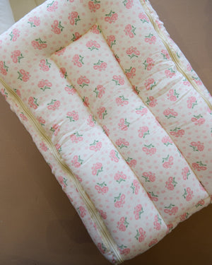 Off-white newborn swaddle sleeping bag with pink and green floral print
