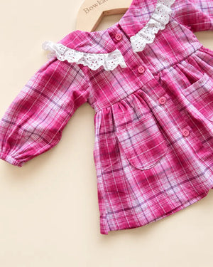 Pink plaid girls' frock with white lace collar, long sleeves, buttons, and front pockets