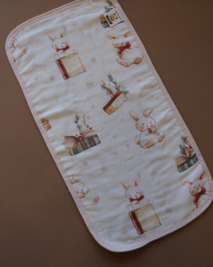 Printed off-white baby burp cloth with playful animal motifs and rounded edges
