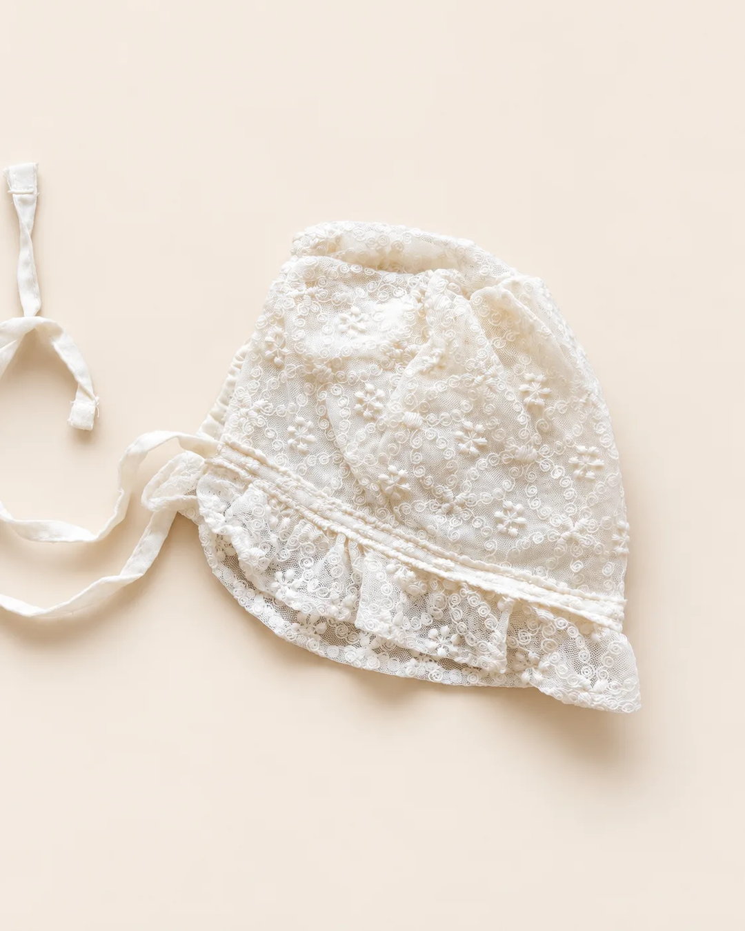 Delicate floral lace baby bonnet with tie straps