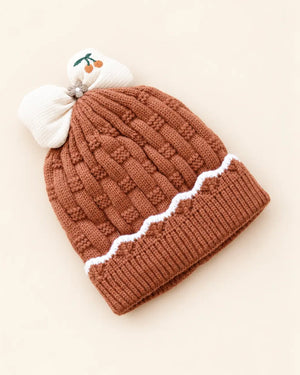 Knitted baby beanie with bow detail, cherry embroidery, and scalloped trim