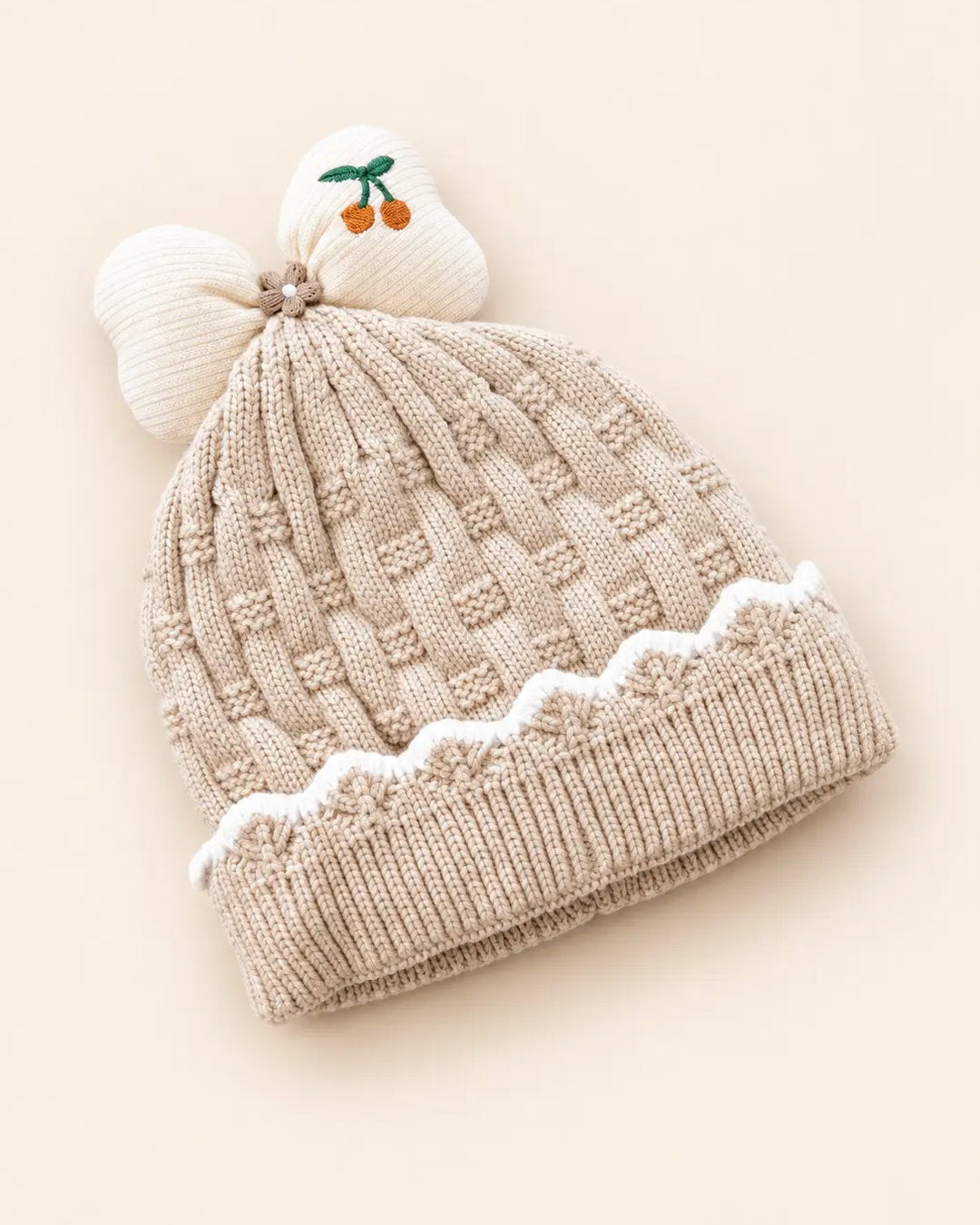 Knitted baby beanie with bow detail, cherry embroidery, and scalloped trim
