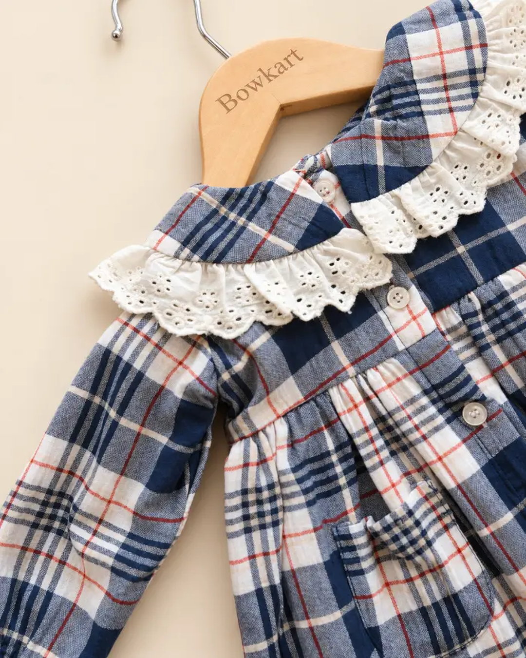 Navy blue plaid girls' frock with eyelet lace collar, long sleeves, buttons, and front pockets