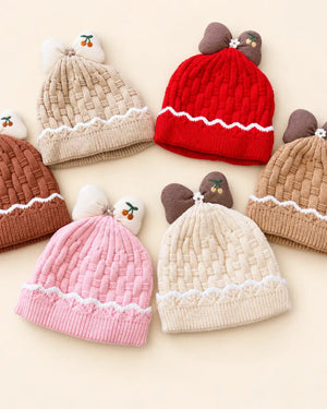 Knitted baby beanie with bow detail, cherry embroidery, and scalloped trim