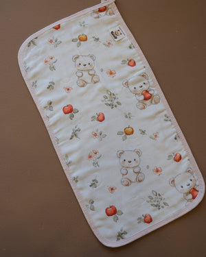 Printed off-white baby burp cloth with playful animal motifs and rounded edges