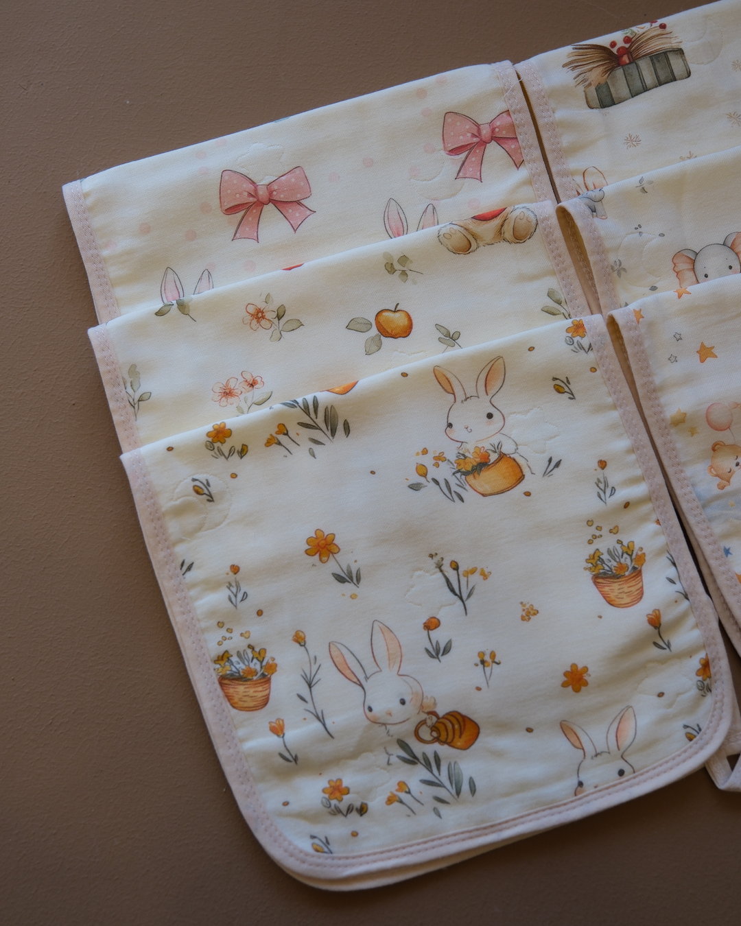 Printed off-white baby burp cloth with playful animal motifs and rounded edges
