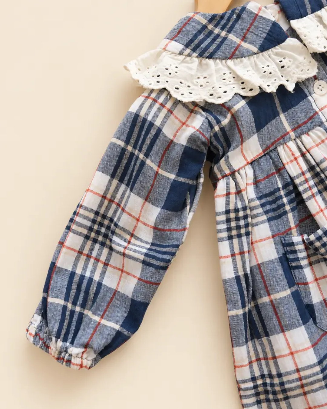 Navy blue plaid girls' frock with eyelet lace collar, long sleeves, buttons, and front pockets