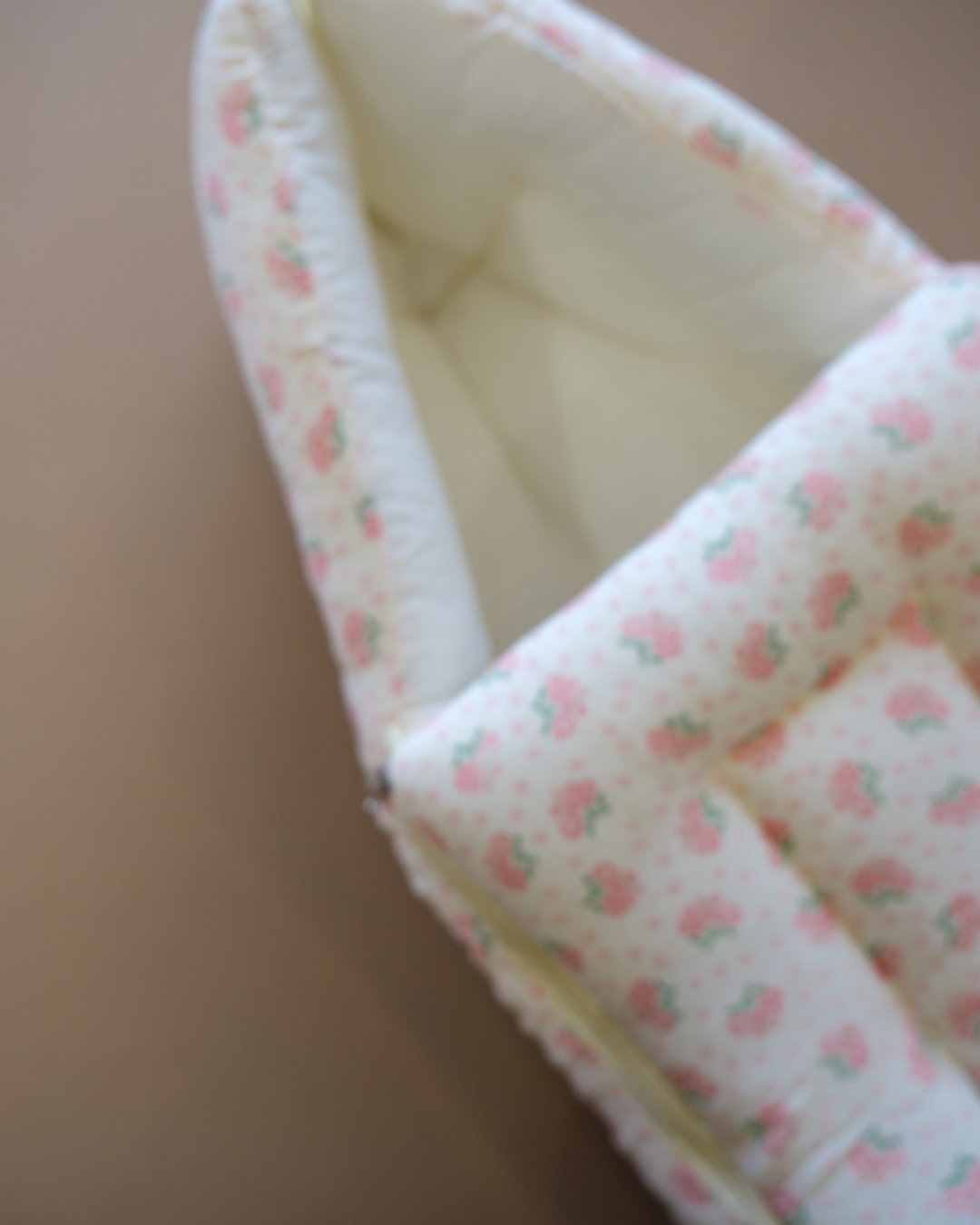 Off-white newborn swaddle sleeping bag with pink and green floral print