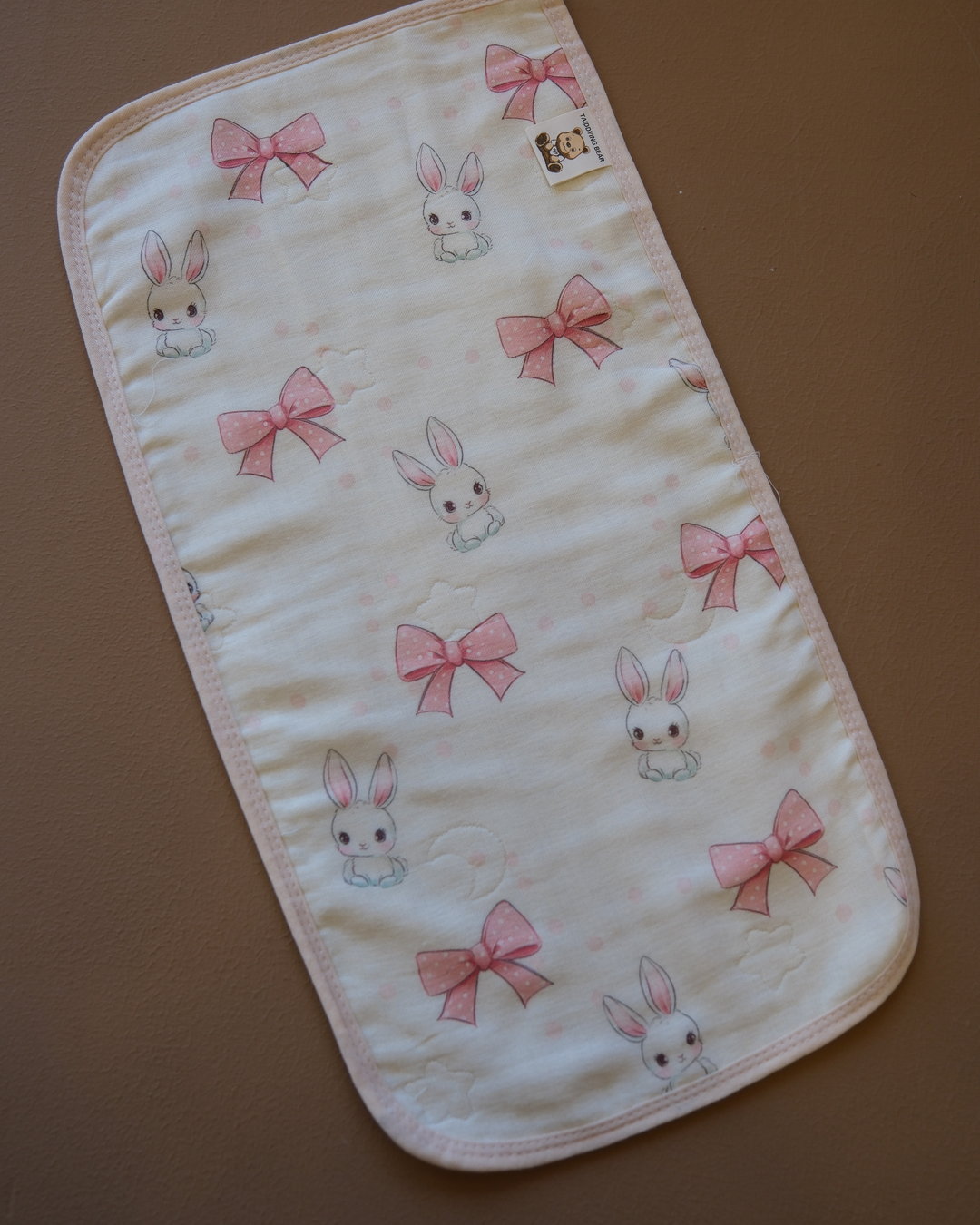Printed off-white baby burp cloth with playful animal motifs and rounded edges