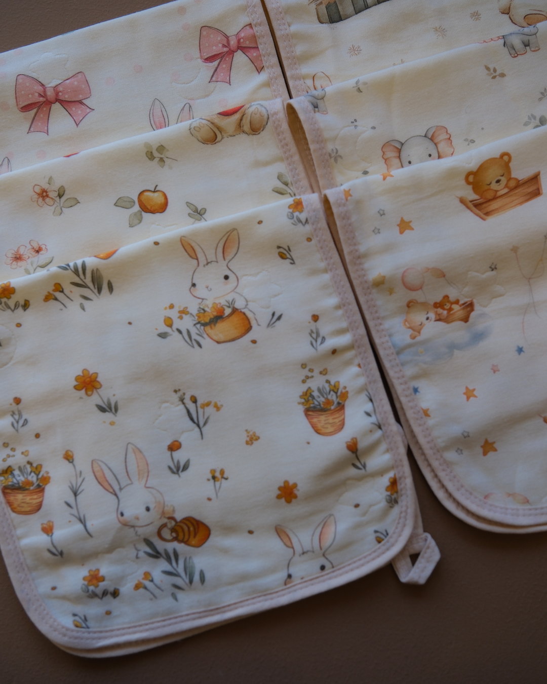 Printed off-white baby burp cloth with playful animal motifs and rounded edges