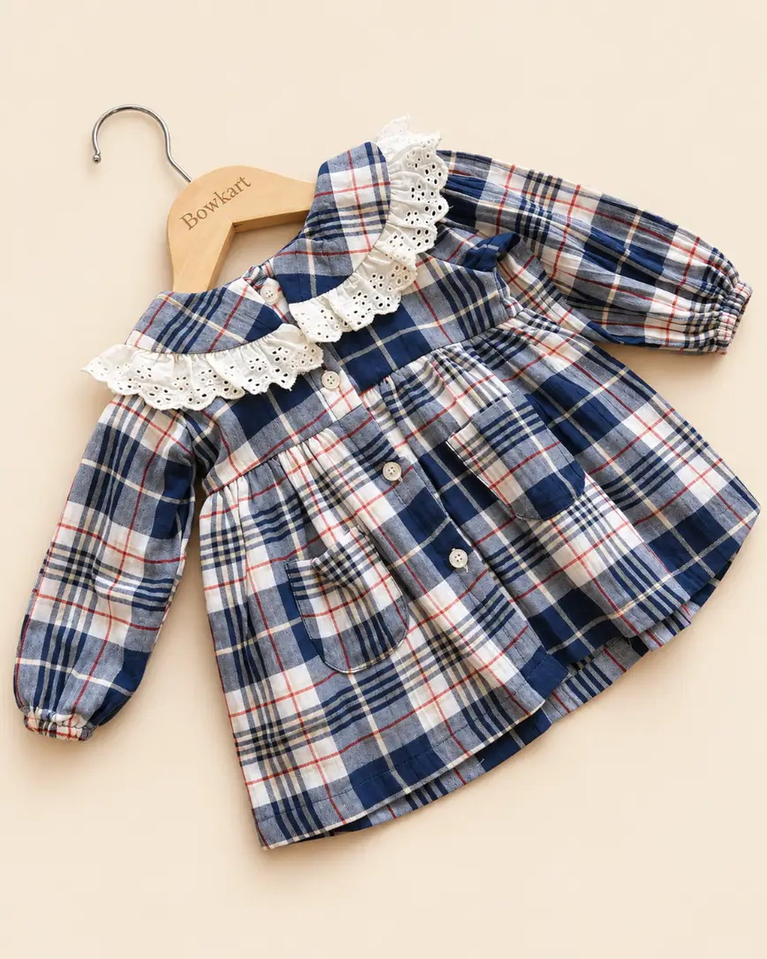 Navy blue plaid girls' frock with eyelet lace collar, long sleeves, buttons, and front pockets