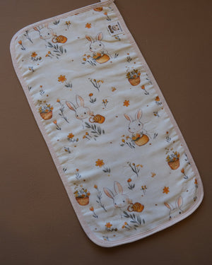 Printed off-white baby burp cloth with playful animal motifs and rounded edges